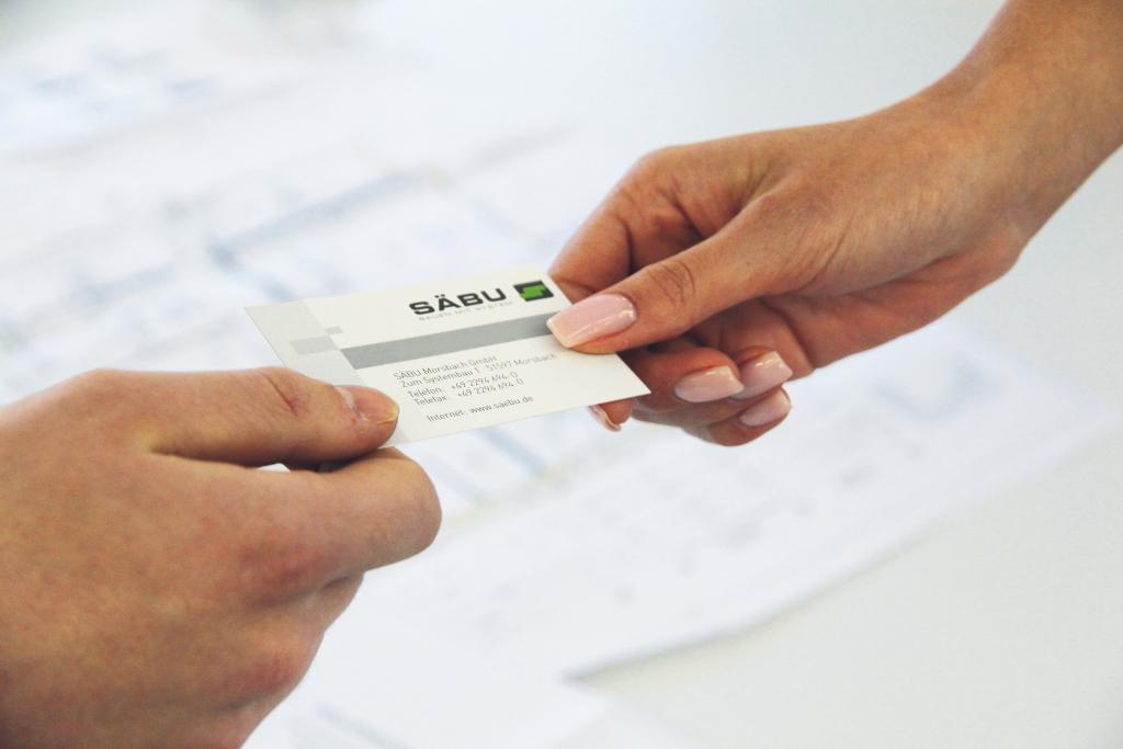 Modulbau Vertriebsmitarbeiter überreicht Visitenkarte an Kunden