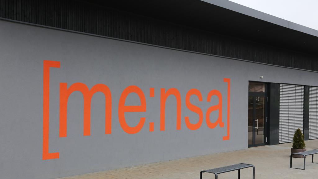 Orange-coloured "Mensa" lettering on the façade of the PAGS school in Kühlsheim